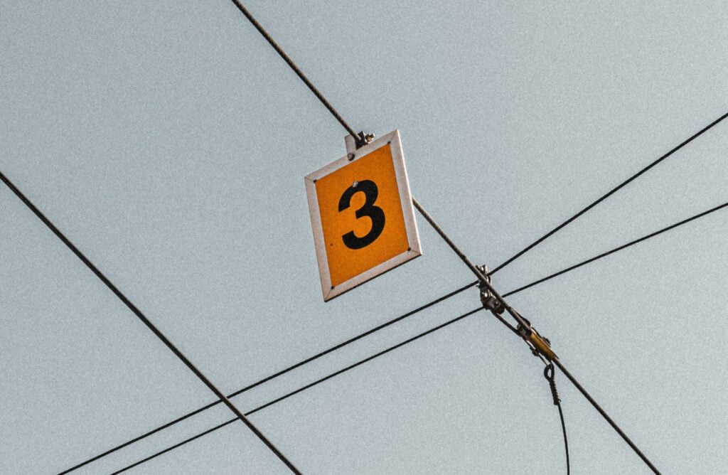Yellow 3 signboard hanging from cable